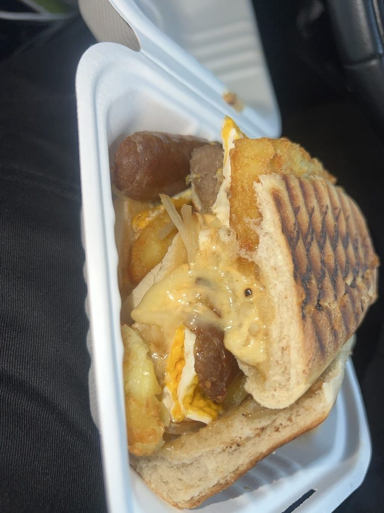 A toasted panini with melted cheese, egg and sausage
